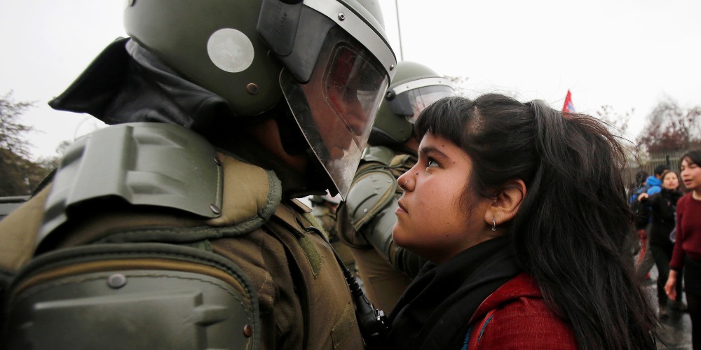 A demonstrator looks at a riot policeman during a protest marking the country's 1973 military coup in Santiago, Chile